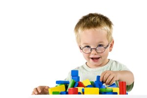 Junge mit Brille spielt mit Baukloetzen