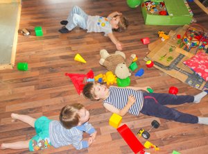 Kinder liegen in chaotischem Kinderzimmer auf dem Boden