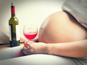 schwangere Frau mit einem Weinglas in der Hand
