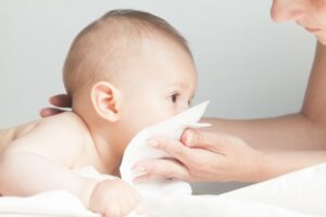 mutter putzt ihrem kranken baby mund und nase ab