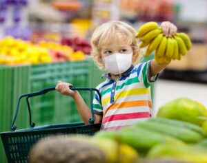 kind hält bananen und einkaufskorb im supermarkt