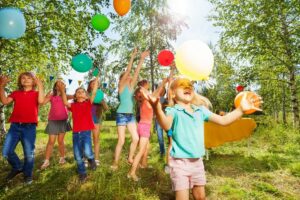 kinder spielen bei einem gruppenspiel draußen mit luftballons