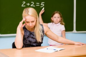 verzweifelte Lehrerin mit einem Kind, dass unfähig ist, eine Matheaufgabe zu lösen
