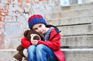 Kind umarmt Bär und ist traurig