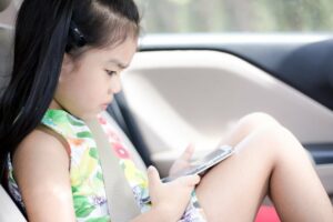Kind spielt bei Autofahrt an Handy