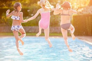 drei Mädchen springen in einen Swimming-Pool