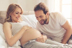 Paar schaut mit Vorfreude auf den Bauch der schwangeren Frau