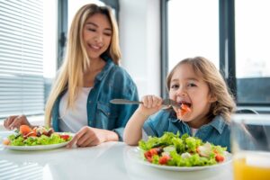 Mutter und Tochter essen gemeinsam je einen bunten Salat